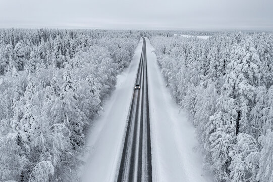 Overhead view of car driving on slippery empty road in the snowy forest, Lapland, Finland