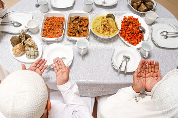 Top view of family hands praying dua together before eat special dish at dining room during eid mubarak moment. 
