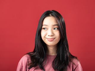 A close-up portrait of a young Indonesian (Asian) woman wearing a pink shirt. Isolated with a red background