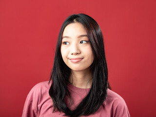 A close-up portrait of a young Indonesian (Asian) woman wearing a pink shirt. Isolated with a red background