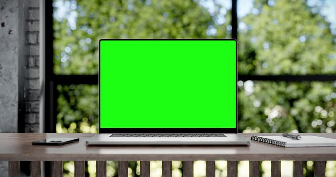 Laptop with blank green screen. Zoom in footage with trees swaying or moving in the wind. Home interior or loft office background, looped 4k 30fps. 3d render