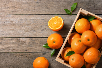 Top view of fresh oranges in wooden crate on wooden table.