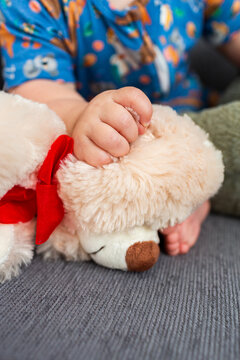 Baby hand holding onto plush toy teddy bear ear