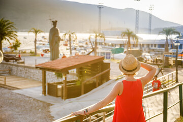 Rear view of a woman in a straw hat standing on a seafront in Herceg Novi town