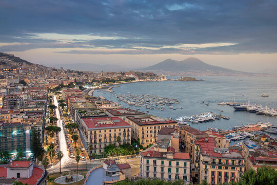 View of Naples downtown at sunset with Vesuvius volcano in background, Campania, Italy.