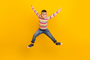 Fototapeta na wymiar Full length photo of active kid boy jumping up raising hands isolated on vibrant color background