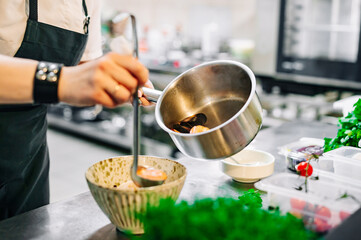 woman chef cooking seafood soup on restaurant kitchen
