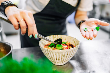 woman chef cooking seafood soup on restaurant kitchen