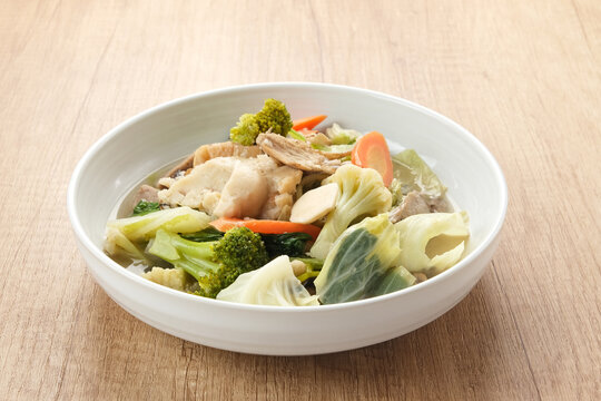 Capcay, stir fried vegetables with shrimp, meatballs and chicken. Served in white plate
