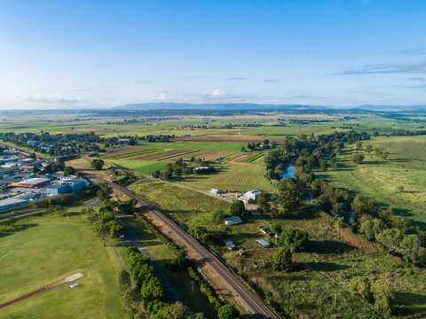 Aerial view of long jump track and pit with railway line and vegetable farm at the edge of town