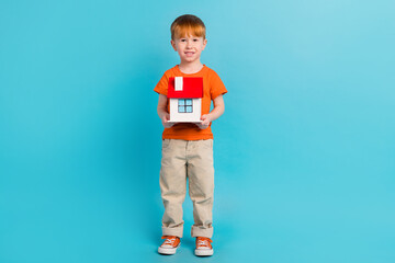 Full length photo advert of cute charming boy wear stylish clothes hold house dream buy house isolated on cyan color background