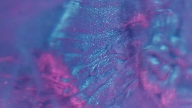 Vertical video. Neon fluid. Ink splash. Sparkling frost. Defocused blue pink color light glitter paint drop motion on cube edge in water abstract background.