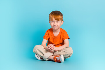 Portrait of positive cheerful boy wear orange stylish clothes relax rest good mood empty space isolated on cyan color background