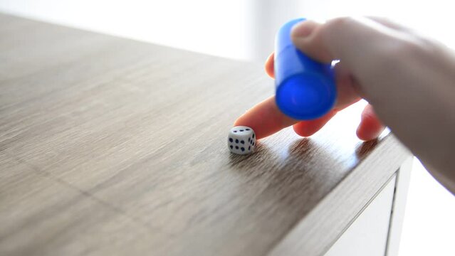 Mano lanzando dados sobre mesa de madera. Buena suerte. Concepto. Tiempo real.