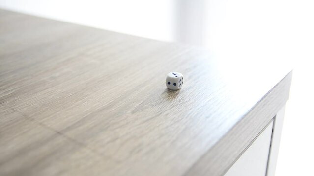 Mano lanzando dados sobre mesa de madera. Buena suerte. Concepto. Tiempo real.