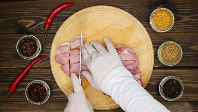 The chef cuts the meat into large pieces. Pieces of meat on a cutting board on a wooden table. Pickling spices, fresh red hot chili pepper, dried cloves, black peppercorns, mustard peas, zira, cumin