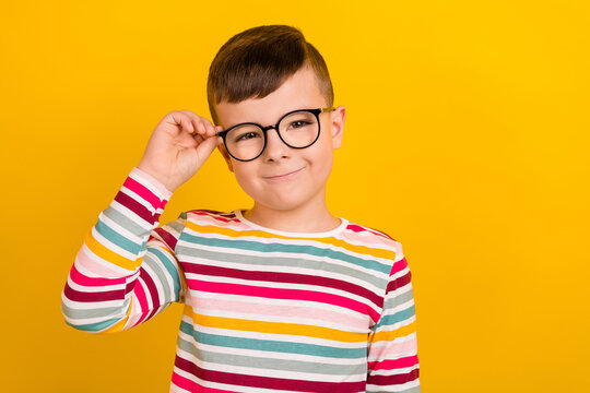 Photo of smart clever cute boy wear striped stylish clothes hand touch eyewear optics shop empty space isolated on yellow color background