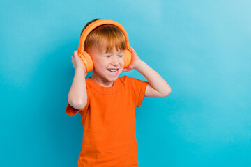 Photo of cheerful positive glad cute boy listen music mp3 player empty space isolated on cyan color background