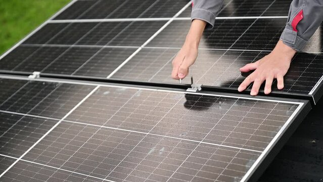 Man technician mounting photovoltaic solar panels on roof of house. Close up engineer installing solar module system with help of hex key. Concept of alternative, renewable energy.