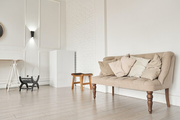 A beige sofa with pillows near the wall next to a small table. Part of the interior with copy space.High quality photo