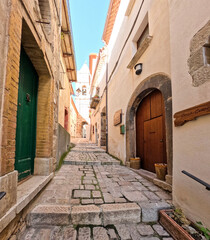 Obraz premium A narrow street among the old houses of Civitacampomarano, a historic town in the state of Molise in Italy.