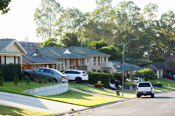 Cars parked in driveways and houses in a row down street