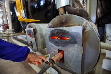 Closeup photo of biogas plant furnace flame and operator's hand