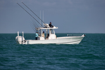Three fishermen on a center console fishing boat in the ocean.