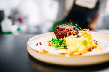 Chef cooking Grilled beef steak filet mignon with potato and sauce on restaurant kitchen