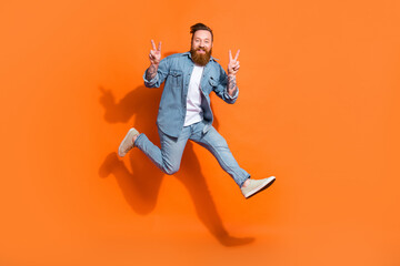 Fototapeta na wymiar Full body photo of energetic man jumping demonstrate v-sign isolated on orange color background