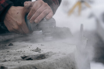 Worker grinds granite surface with an electric grinder. Close-up