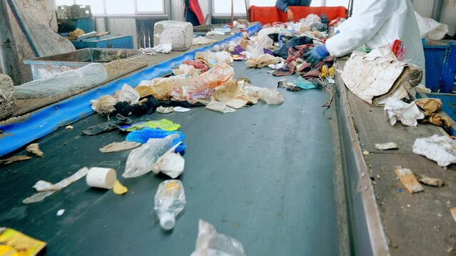 Workers in special wear sorting garbage on a conveyor belt at waste sorting plant