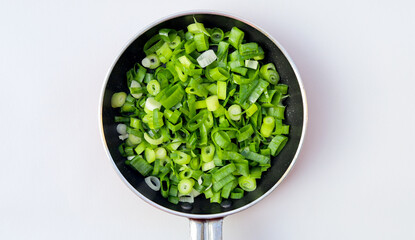 Chopped spring onions or chives isolated in frying pan on white background, top view