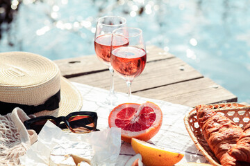 Romantic sunset dinner on the beach. Table honeymoon set for two with luxurious food, glasses of rose wine drinks in a restaurant with sea view. Summer love, romance date on vacation concept.   