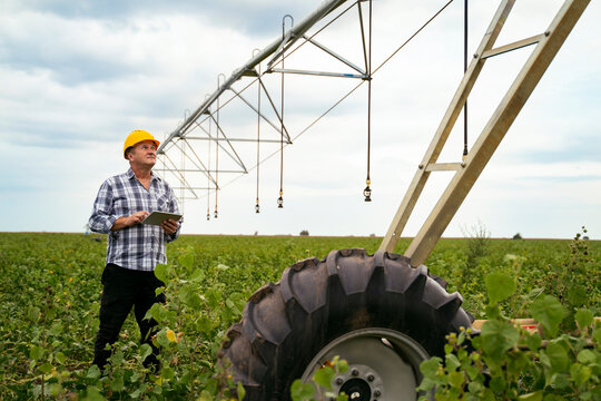 Man agriculture expert, farmer standing near watering systems on the field with digital tablet 