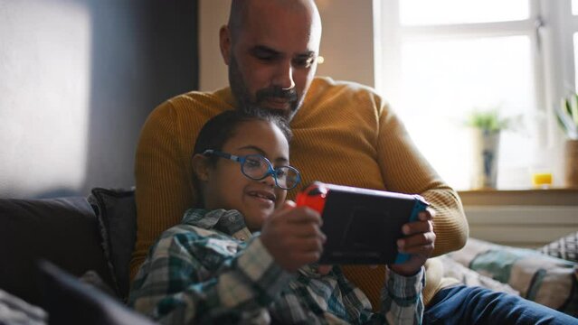 Multiracial father and son with Down syndrome playing computer game - Powered by Adobe