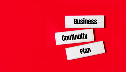 Three wooden blocks with the text BCP Business Continuity Plan on a bright red background. Copy space