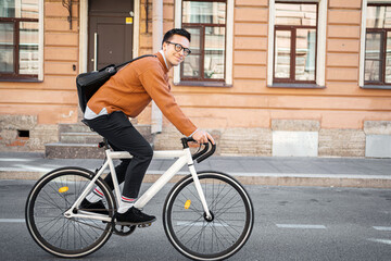 A teenage male freelancer going to the office for work Monday by bike eco transport in the city.
