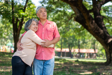 Portrait of lovely elderly couple hugging each other with love and happiness in a park outdoor. Happy smiling Elderly couple enjoying with positive emotions at garden