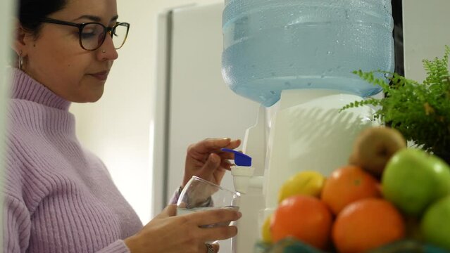 Latin woman drinking water from water dispenser