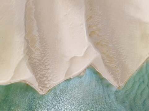 Aerial view of patterns in white sand bars surrounded by blue sea