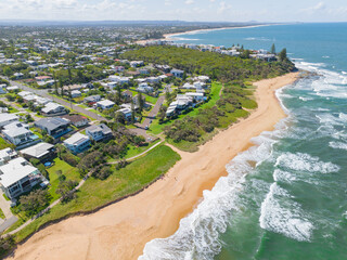 Aerial view of housing near waves crashing on a sandy beach