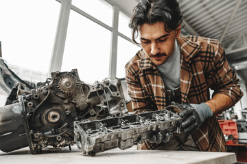 Workman disassembling car engine at the working table of the car service garage