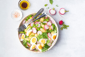 Spring salad with baby potatoes, radishes, farmer organic  eggs and green peas and herbs, seasoned with olive oil, mustard sauce, balsamic and lemon.  Spring vegetarian diet, clean healthy lunch