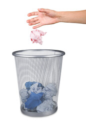 Hand throwing out paper into trash basket isolated on white