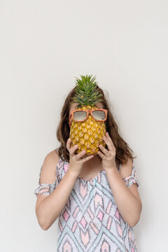 teen girl with pineapple over her face