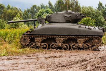 Fototapeta na wymiar An American World War II Sherman M41A1 76 (w) tank stands in a field in the mud. Bielsko-Biała, Poland