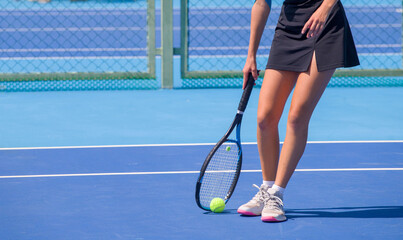 A girl plays tennis on a court with a hard blue surface on a summer sunny day