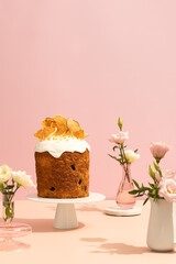 freshly-baked Easter cake on a white plate. beautifully decorated and surrounded by flowers, set against a neutral pink background. Perfect for Easter greetings or springtime promotions.