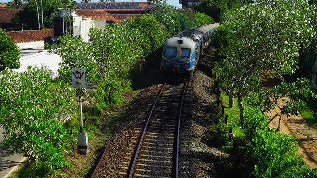 The old train leaves into the distance in a tropical city